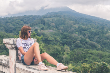 Beautiful young woman in sunglasses and with backpack on tropical jungle background. Bali island, Indonesia. Asia.