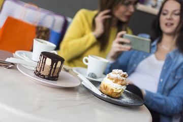 cakes and coffee on the table and two girls in the background