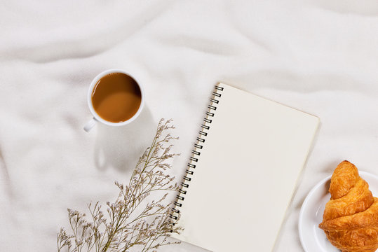 Cozy and tasty breakfast with coffee mug and croissant with paper note.