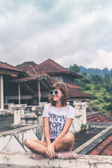 Beautiful young woman in sunglasses sitting on tropical jungle background. Bali island, Indonesia. Asia.