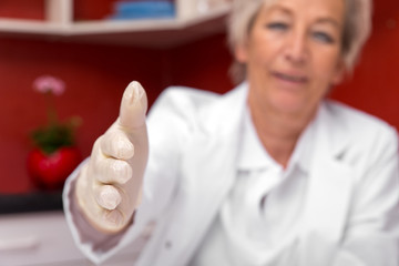 Ärztin mit Handschuhen streckt die Hand zur Begrüßung aus