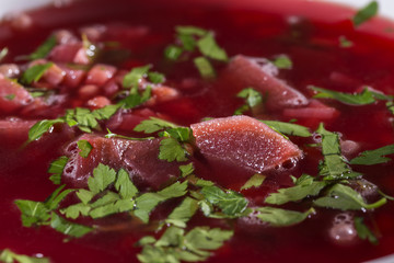 Traditional Romanian beet borscht with green parsley in white bowl