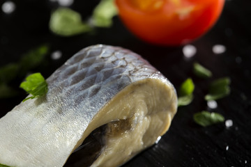 Piece of marinated herring fish with salt and parsley