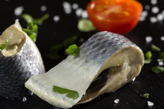Marinated herring fish with salt and parsley on slate