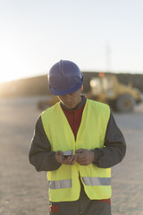 Worker looking smartphone after working in construction having a break