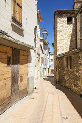 Fototapeta na wymiar alone street without people and shops in summer day with shadows and blue sky in provence in France