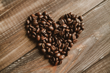 Roasted coffee beans at wood background. Concept coffee love heart