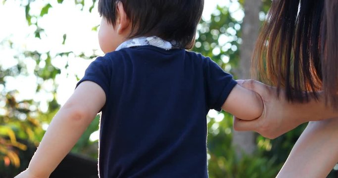 child boy holding hand mother walking naughty in the park