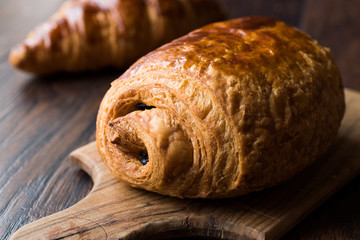Freshly Baked Chocolate Croissant on Wooden Surface.