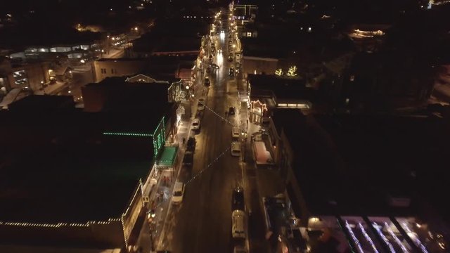 Aerial dolly shot of cars in cool little mountain town on a winter night