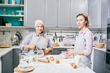 Two confectioners in uniform preparing dough for cake or biscuits in the kitchen