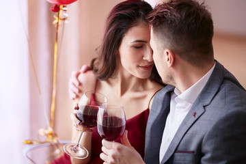 Beautiful couple celebrating Valentine`s day in restaurant, drinking wine, sharing gifts and enjoying each other.