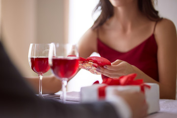 Beautiful couple celebrating Valentine`s day in restaurant, drinking wine, sharing gifts and enjoying each other.
