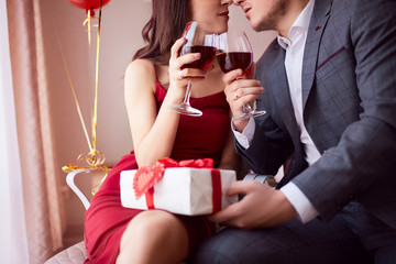 Beautiful couple celebrating Valentine`s day in restaurant, drinking wine, sharing gifts and enjoying each other.