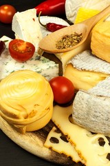 Healthy cheese. Different types of cheeses with tomato and chili pepper on the kitchen board. Preparation of healthy food.