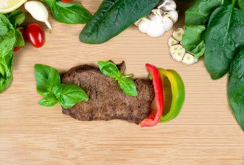 Flat lay of roasted beef steak served with fresh herbs, vegetables and pomegranate grains