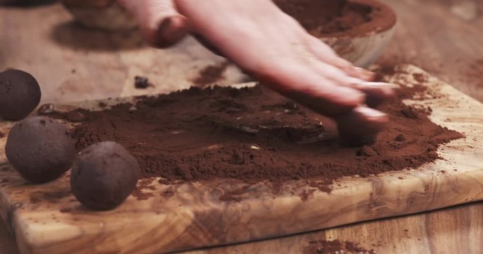 Slow motion handheld shot put truffles in cocoa powder on board