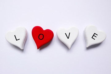 Top view of white and red wooden handcraft heart symbol written with 'LOVE' on white background.  Valentine's day theme.