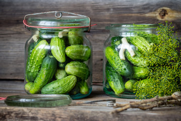Jars of pickled marinated cucumbers on rustic table
