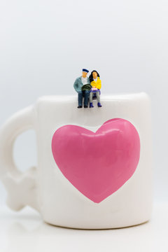 Miniature people :Couple sitting on the glass. Image use for Valentine's day.