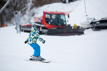 Cute little preschool child in blue jacket, skiing happily on a sunny day