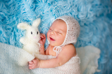 Little cute newborn baby boy, sleeping wrapped in white wrap