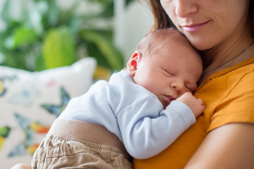 Young mother, holding tenderly her newborn baby boy