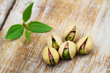 Five pistachio nuts on rustic wooden surface
