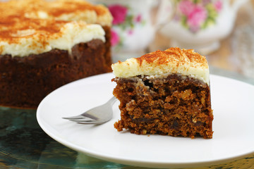 Slice of rich carrot cake with walnuts and marzipan icing
