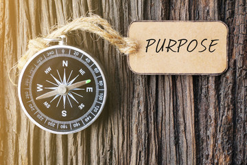 Magnetic compass and paper tag written with PURPOSE on old wooden background. © Yunus Malik