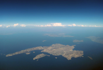 the island of kalymnos from the air with mainland in the distance with blue summer sky and band of...
