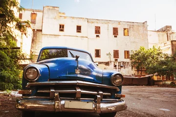 Wall murals Havana old blue american car parked in old havana