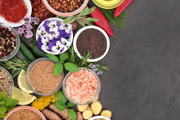 Spice, herb and edible flowers forming an abstract background border on slate. 