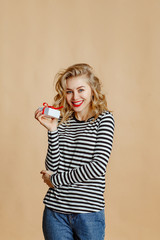 Young beautiful caucasian woman blonde  posing on yellow background. Studio shot. girl opens a small white gift box.