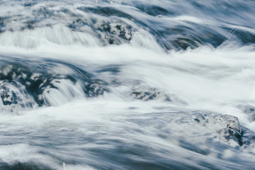 A powerful stream of mountain river. The fast current of water.