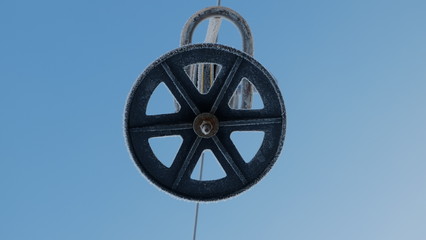 The wheel of the lift in the frost on the background of the blue sky.