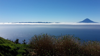 View of mount Pico, the hightest mountain of Portugal, above the clouds from the neighbouring island Sao Jorge at the Azores