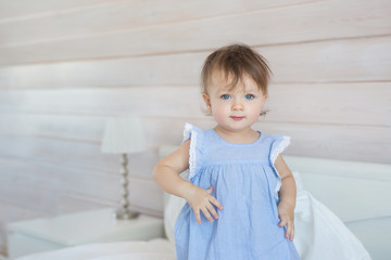 Fototapeta premium Pretty little baby girl stands on a bed in a bedroom