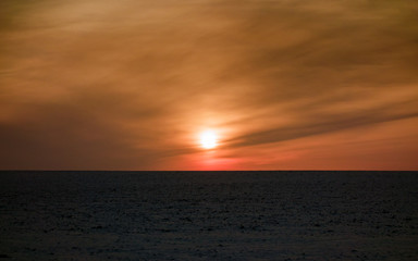Deep colorful winter sunset with snow on black soil