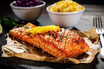 Grilled salmon with vegetables served on black stone plate on wooden table 