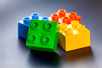 Colorful plastic toy building blocks on gray background
