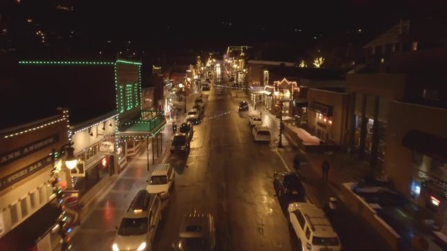 Aerial shot of cars on road in mountain town at night at winter