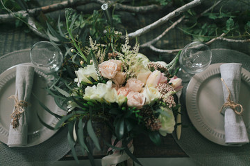 Rustic wedding decoration. A bouquet of different flowers on the decorated table for two.