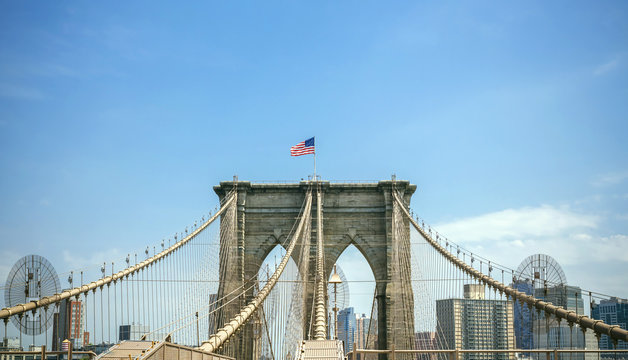 Fototapeta View of Brooklyn Bridge towers over blue sky with Manhattan skyline on background, in New York City