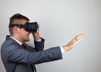 A businessman in a suit, with virtual reality glasses on his eyes, a white background, a delight on his face