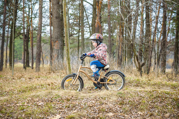 Obraz premium child on a bicycle in the forest in early morning. Boy cycling outdoors in helmet