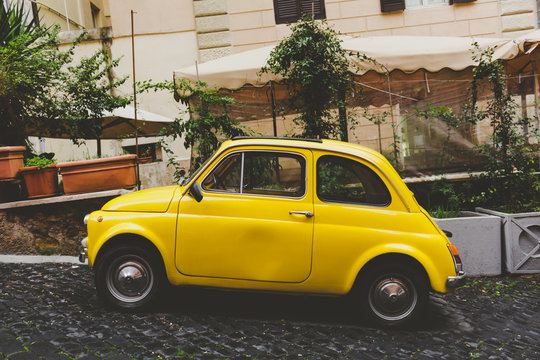 A yellow car in a small street in Rome