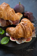 Closeup of croissants stuffed with prosciutto ham and slices of ripe figs, vertical shot, selective focus