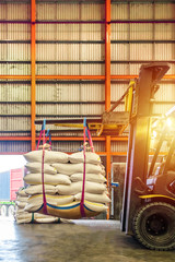 Forklift handling white sugar bags for stuffing into containers outside a warehouse. Distribution,...