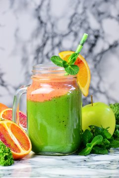 Fresh Green Smoothies with blood oranges. Green smoothie jar on the light background